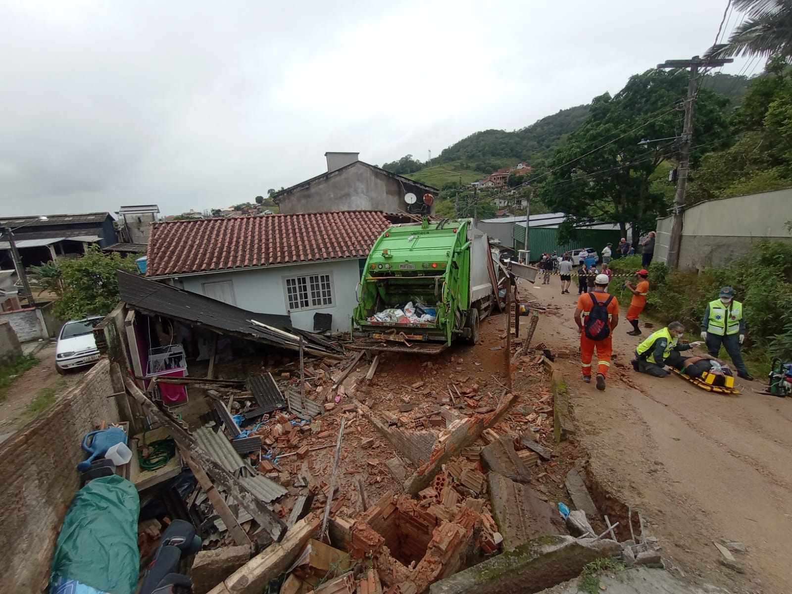 Caminhão de coleta de lixo invade terreno e derruba parte de residência após perder os freios